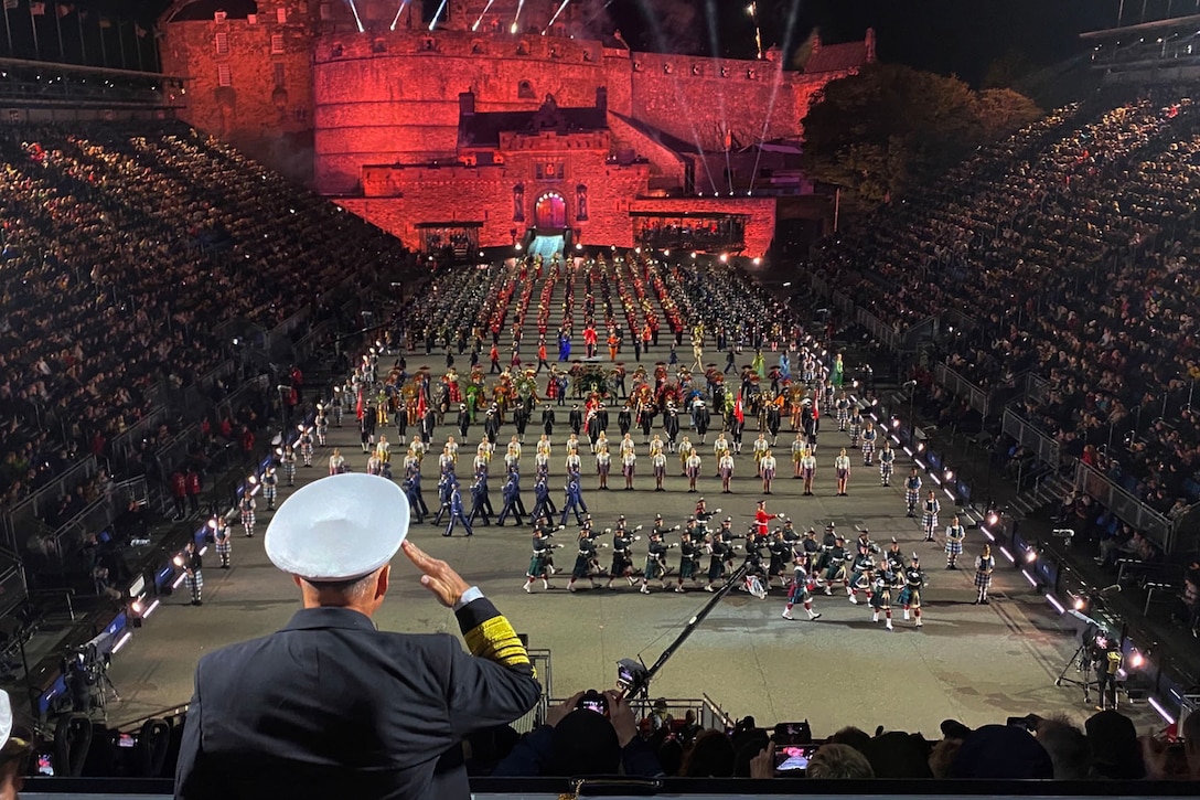 A Navy officer salutes in a large stadium.