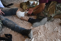 Capt. Tyrome Brown, from Tyndall Air Force Base, Fla. cuts bandages after wrapping the leg of mock patient at Cannon Air Force Base, N.M., Aug. 16, 2022. The Medic Rodeo, hosted by the 27th Special Operations Wing, creates a ready medical force by testing the knowledge and skills of medics across the Air Force. (U.S. Air Force photo by 2nd Lt. Brandon DeBlanc)