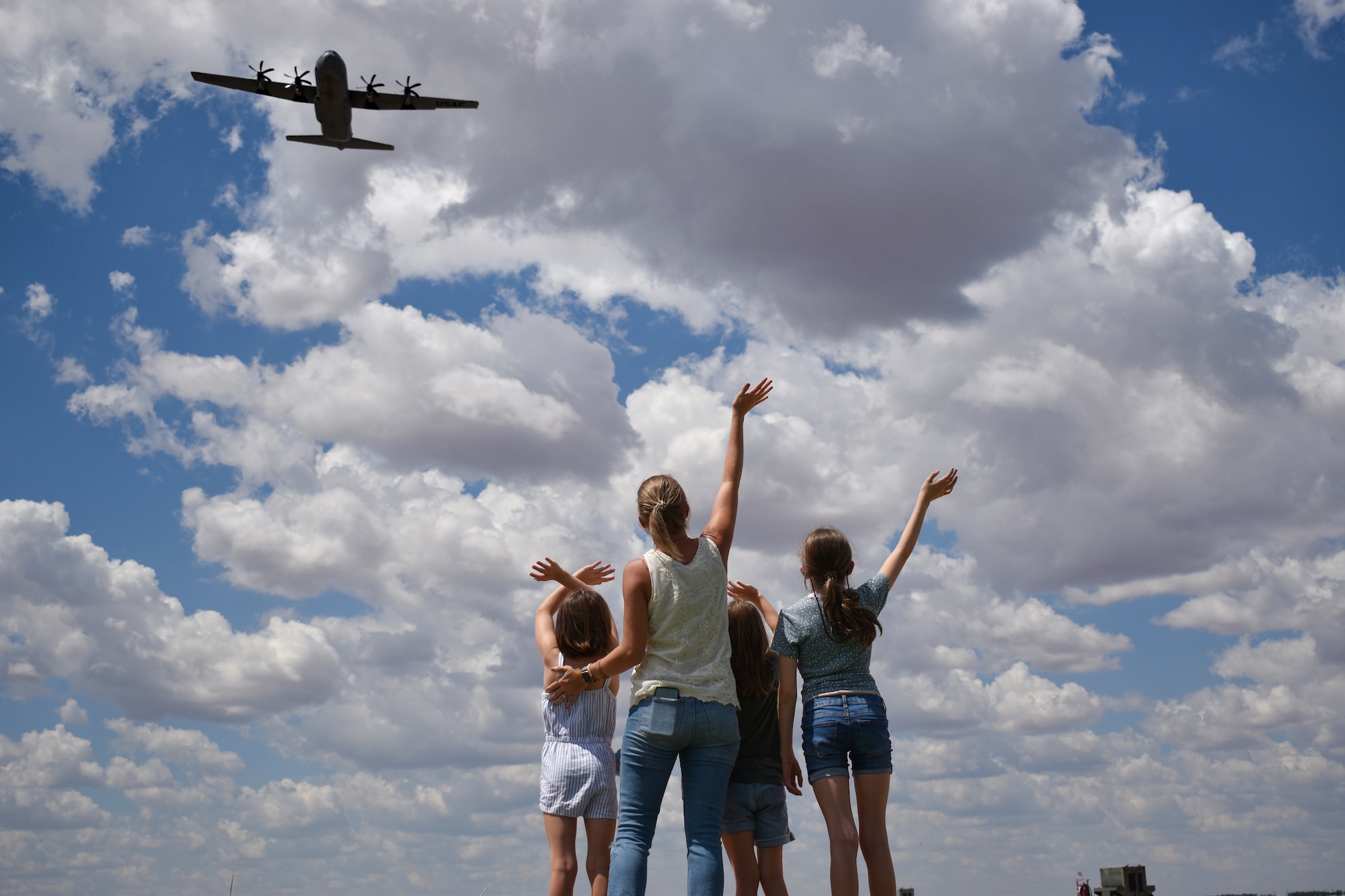 A mother and three girls wave goodbye as the C-130J model departs with their father for a deployment to CENTCOM Aug. 26, 2022. The father later texted 317th Leadership, “I swear I was waving back to my family below.” The C-130 unit’s deployment in support of U.S. Central Command taskings marks the first implementation of the Air Force Generation model in Air Mobility Command. (U.S. Air Force photo by 1st Lt. Kaitlin Cashin)
