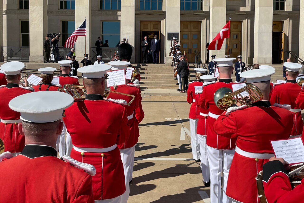 A Marine band plays as two men stand at the top of the Pentagon steps.