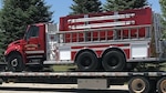 A firetruck sits on a flatbed trailer.