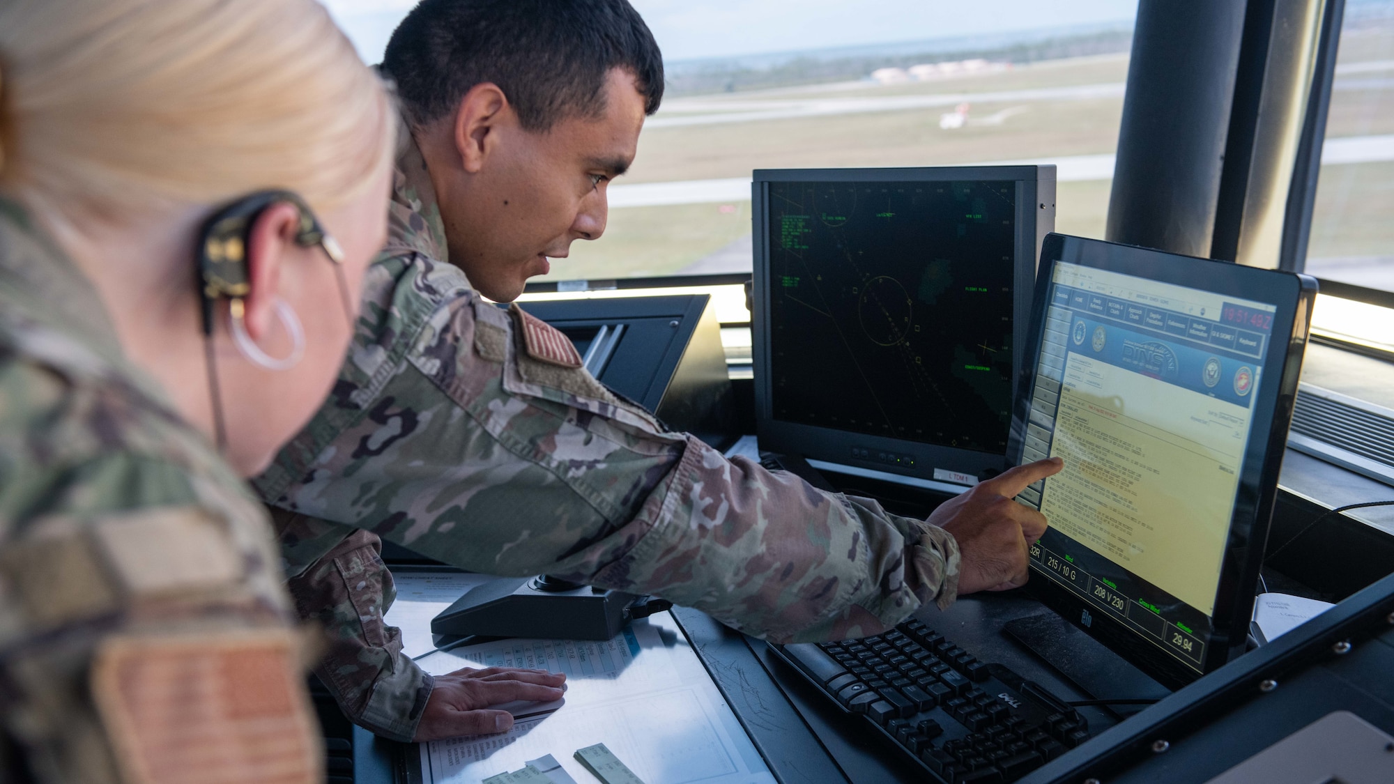 Airmen look at a computer screen.