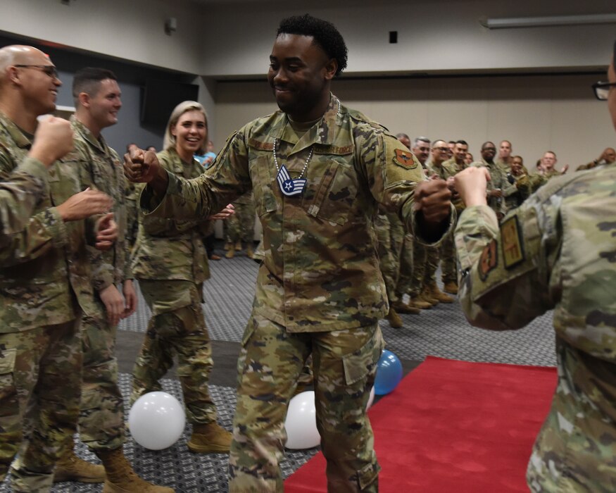 U.S. Air Force Senior Airman Joseph Vaughan, 17th Force Support Squadron assignments section lead, makes his way through the gauntlet, receiving fist bumps from noncommissioned officers during the Staff Sergeant Release Party at Goodfellow Air Force Base, Texas, Sept. 1, 2022.  Vaughan and the other 17th Training Wing senior airmen selected to staff sergeant will make the transition to NCO in the coming months.  (U.S. Air Force photo by Airman 1st Class Zachary Heimbuch)