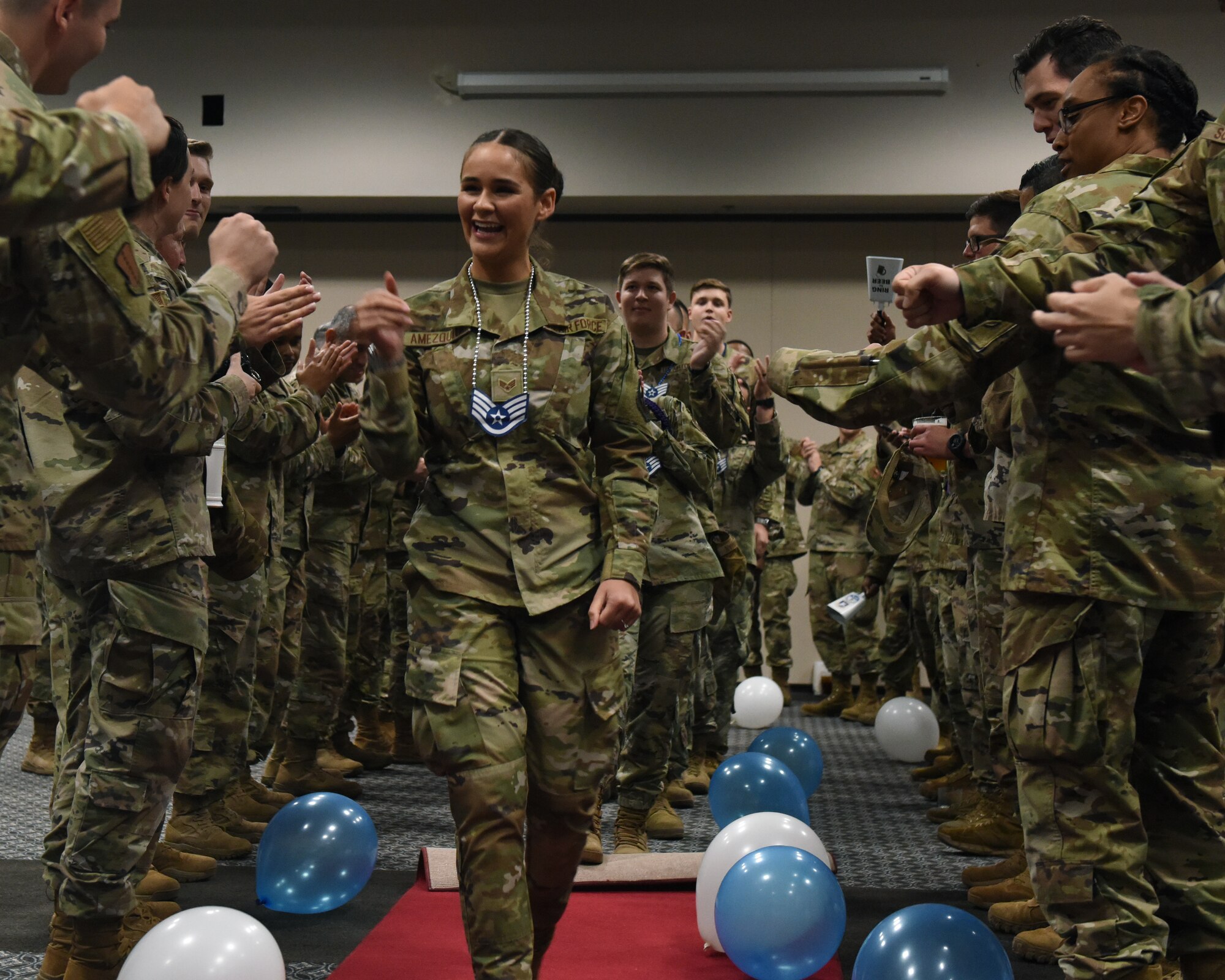 U.S. Air Force Senior Airman Sandy Amezquita, 17 Security Forces Squadron emergency communications center specialist, makes her way through the gauntlet, receiving cheers and fist bumps from noncommissioned officers during the Staff Sergeant Release Party at Goodfellow Air Force Base, Texas, Sept. 1, 2022. Following her walk through the gauntlet, Amezquita and her fellow selectees received certificates from 17th Training Wing leadership.  (U.S. Air Force photo by Airman 1st Class Zachary Heimbuch)