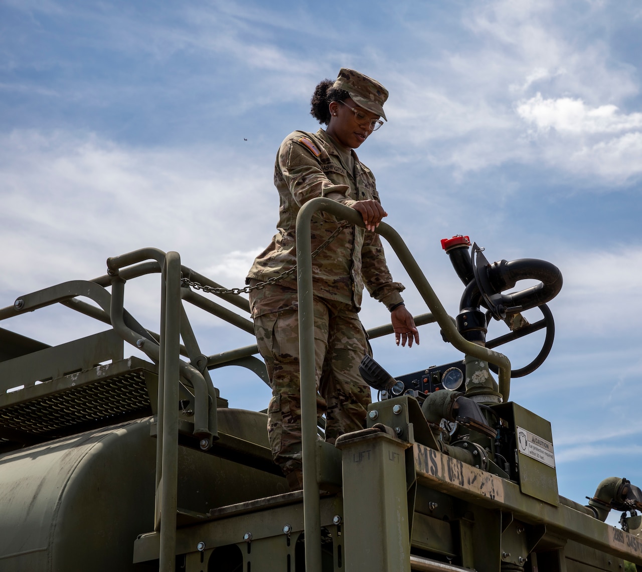 A soldier stands on top of a water truck.