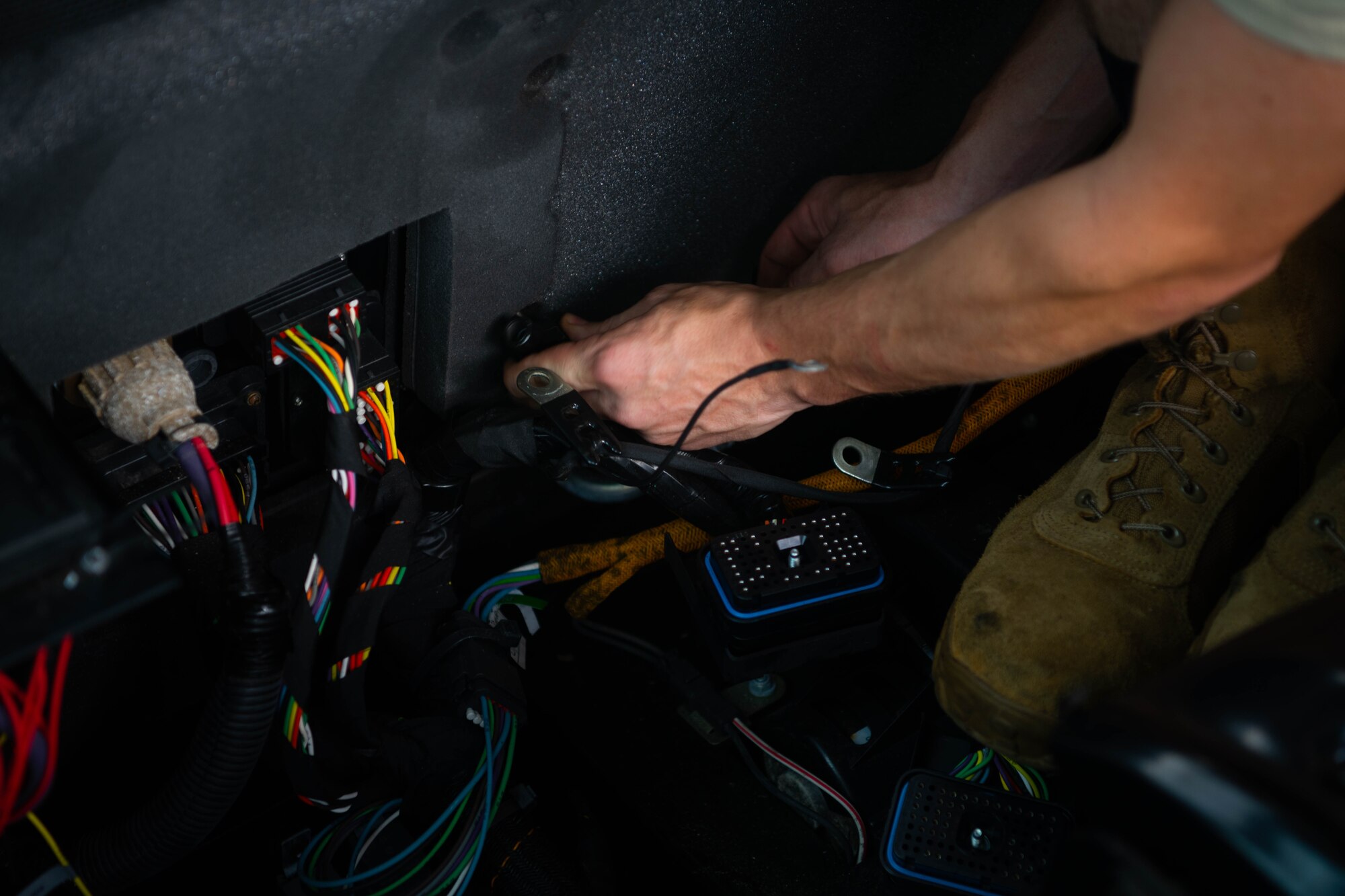 An Airman repairs wiring in a vehicle.