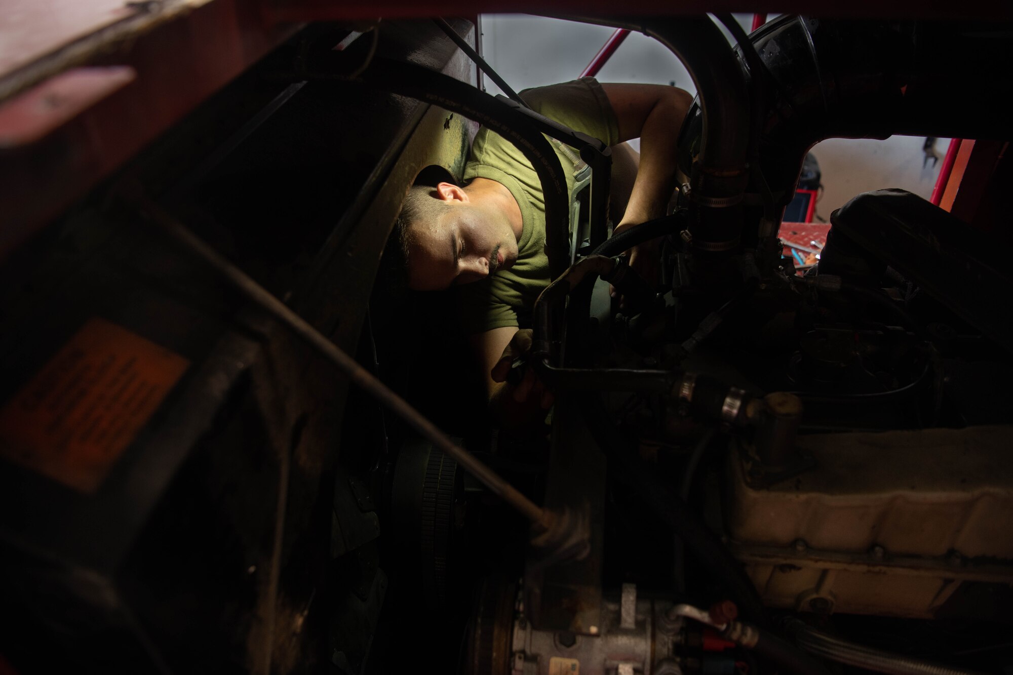 An Airman repairs a fire truck engine.