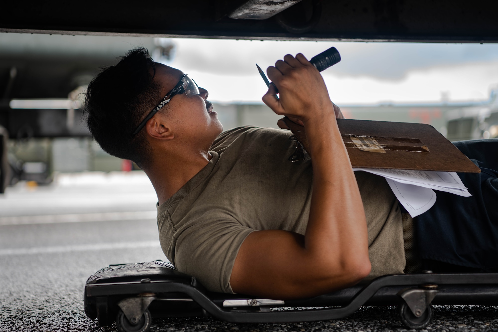 An Airman inspects the underside of a vehicle.