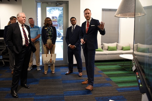 Photo shows group of people standing and speaking in a room