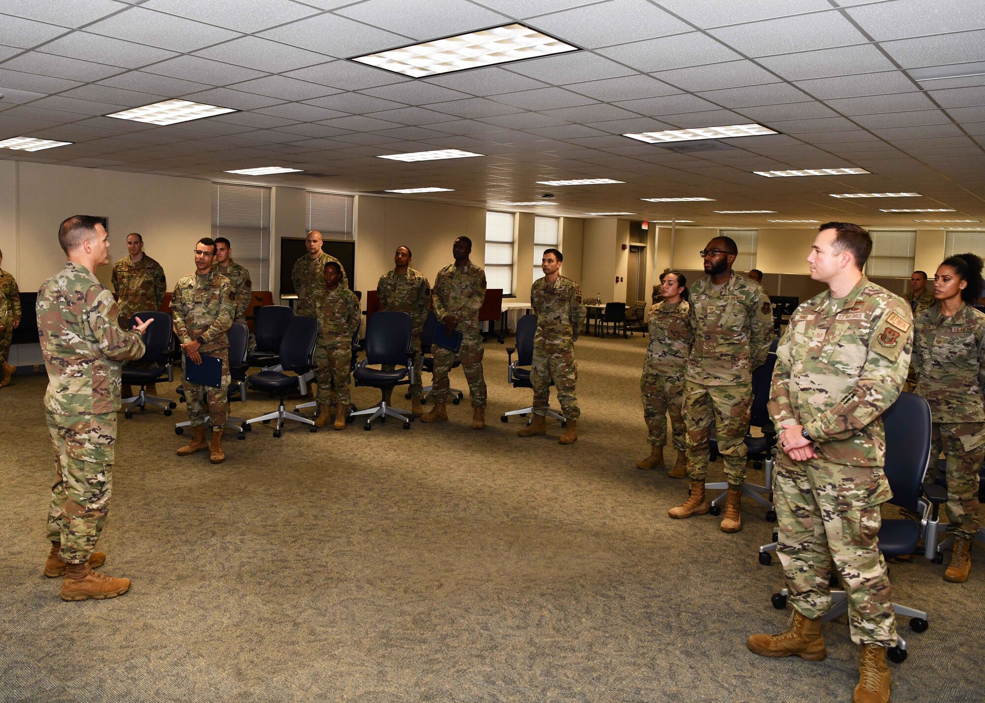 Instructor speaks to group of students standing in a classroom.
