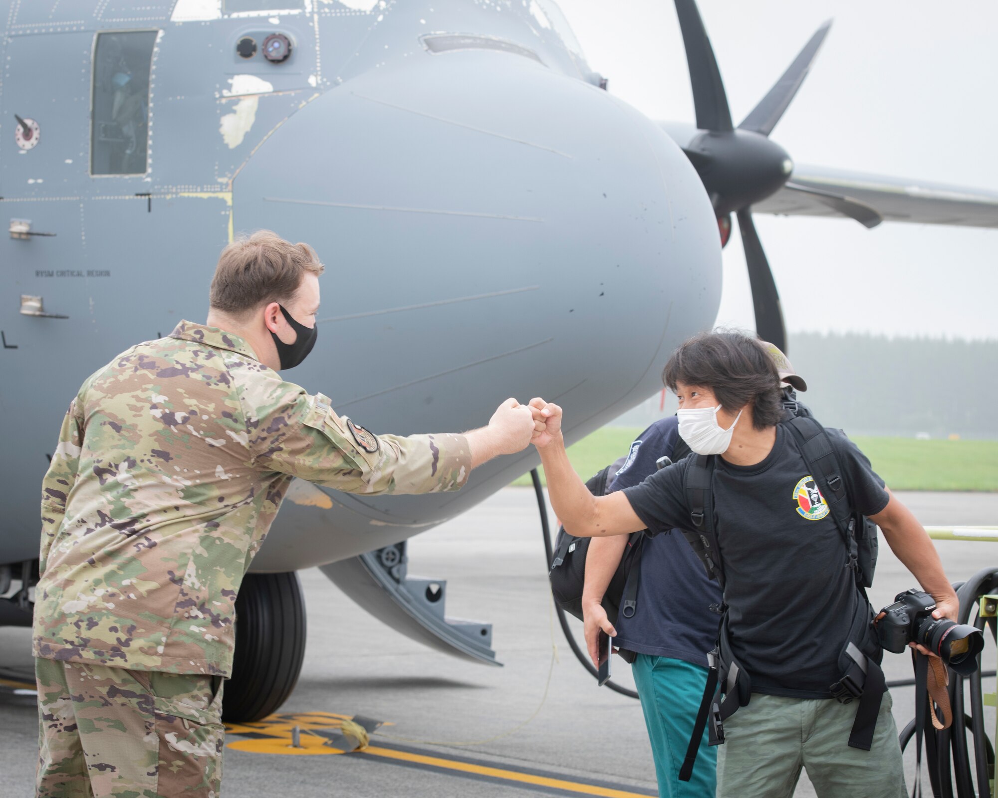Airman 1st Class Spencer Kans, 36th Airlift Squadron loadmaster, bumps fists with a local area aviation enthusiast during a tour at Yokota Air Base, Japan, Aug. 31, 2022.