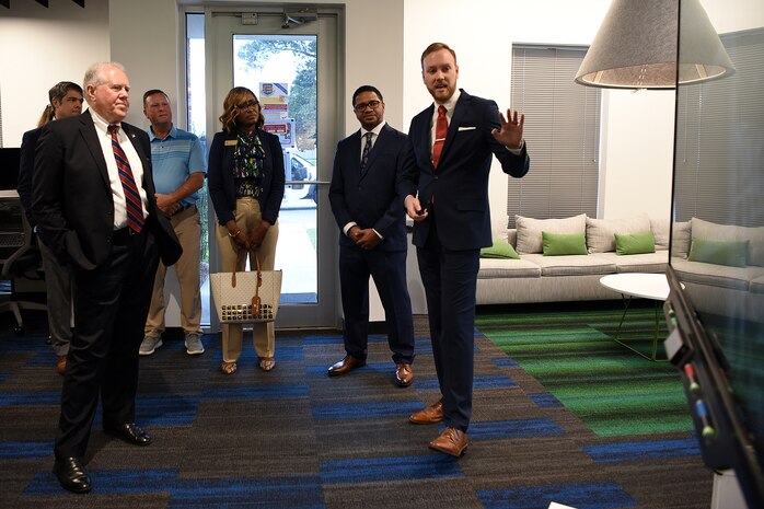 Photo shows group of people standing and speaking in a room