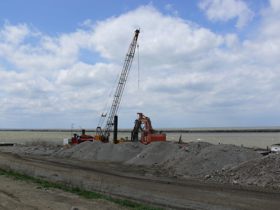 Ryba Marine Construction pump equipment sits along the Dike 12 wall with the Cleveland Breakwater in the background.

