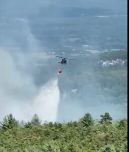 A New York Army National Guard UH-60M Black Hawk helicopter drops 600 gallons of water on a wildfire along a ridgeline in Minnewaska State Park Preserve in the Hudson Valley near Ellenville, New York, Aug. 30, 2022. The New York National Guard deployed two Black Hawks to support firefighting operations at the request of the New York State Department of Environmental Conservation.