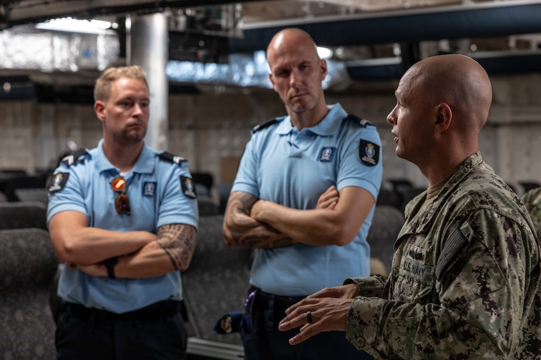 Chief Operations Specialist Robert Timothy Weier, assigned to the Spearhead-class expeditionary fast transport ship USNS Burlington (T-EPF-10), speaks with Dutch military police while providing a tour of the ship during a theater security cooperation event, Aug. 9, 2022. Burlington is deployed to the U.S. 4th Fleet area of operations to support expeditionary maintenance to deployed littoral combat ships operating in the region and conduct theater security cooperation engagements to maintain access, enhance interoperability and build enduring partnerships in the Caribbean, Central and South America.