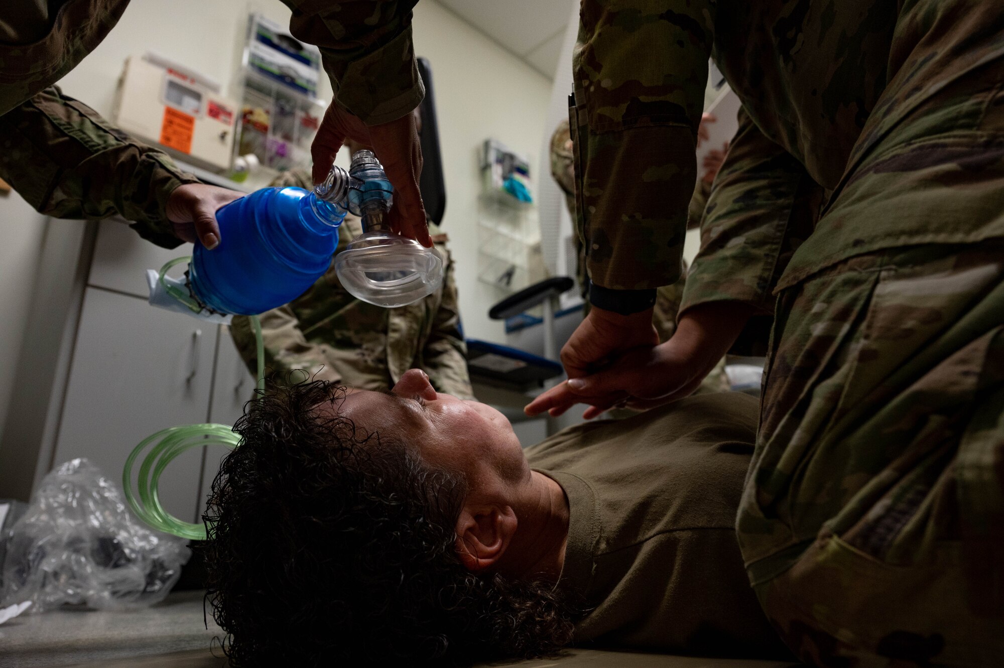 Airmen lowers breathing mask to patient face