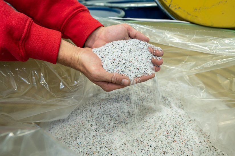 Photo of hands holding small pieces of plastic used for blasting