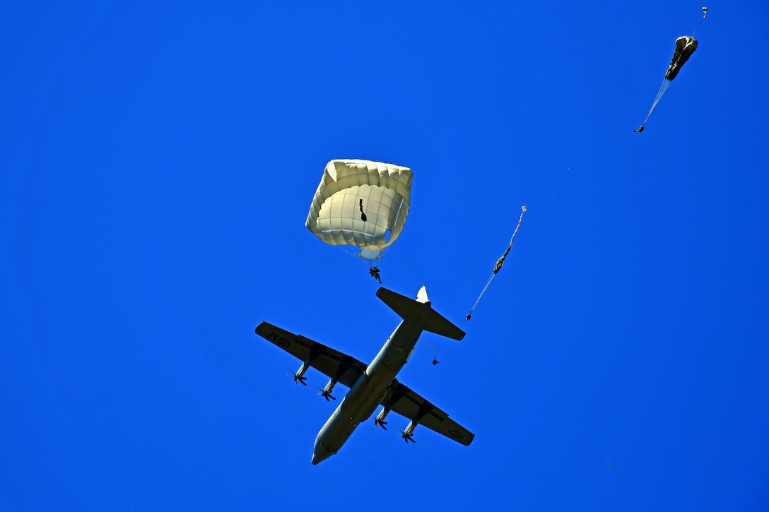 Paratroopers jump from an aircraft.