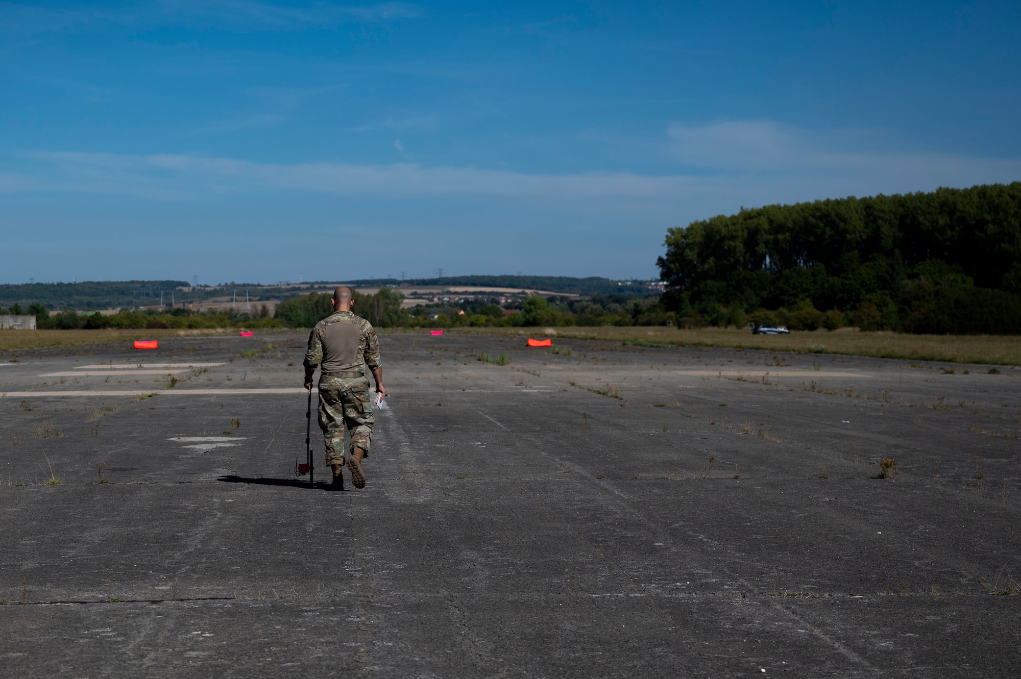 U.S. Air Force Master Sgt. Garrison Medina, 86th Operations Support Squadron, Air Traffic Control Standards and Evaluations noncommissioned officer in charge, measures distance on a runway in preparation for an airdrop at Base Aérienne Grostenquin, France, Aug. 26, 2022.