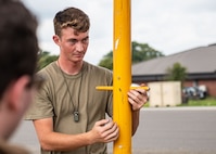 An Airman prepares a tow bar while another looks on.