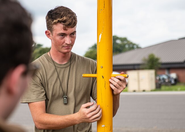 An Airman prepares a tow bar while another looks on.