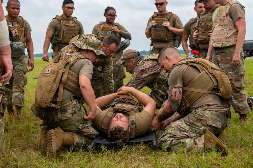 Airmen set another Airman on a stretcher.