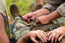 Airmen secure another Airman to a stretcher.