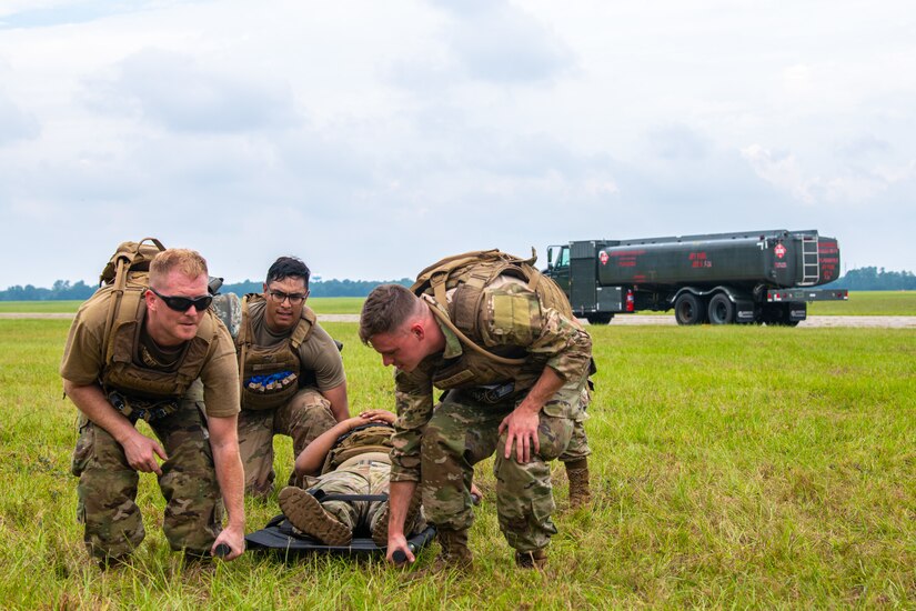 Airmen prepare to carry another Airman on a stretcher.