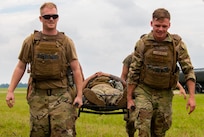 Airmen carry another Airman on a stretcher.