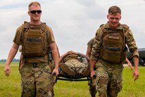 Airmen carry another Airman on a stretcher.