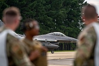 An F-16 prepares for take off as Airmen watch.