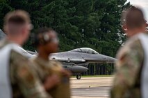 An F-16 prepares for take off as Airmen watch.