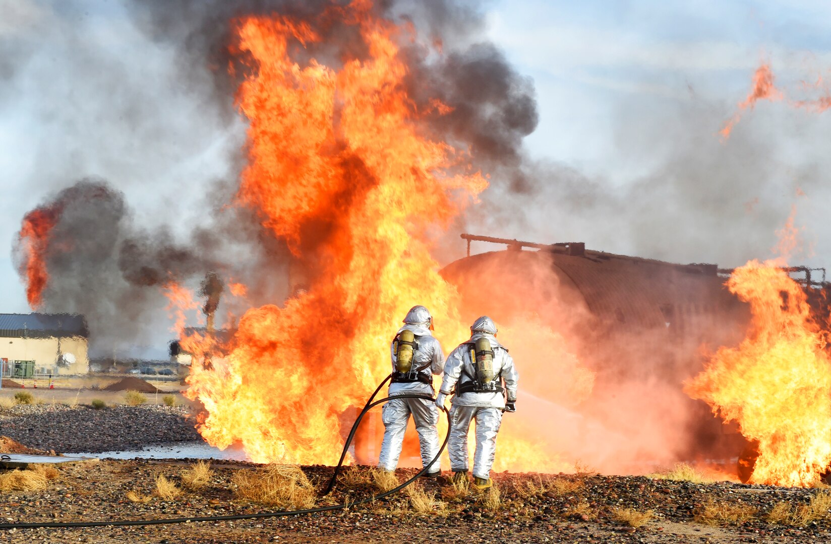 Firefighters with the 56th Civil Engineer Squadron and Gila Bend Fire Department spray water onto a fire during training Dec. 7, 2016, at Luke Air Force Base, Ariz.