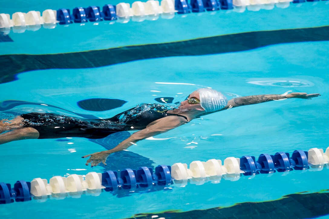 A swimmer does the backstroke in a pool.
