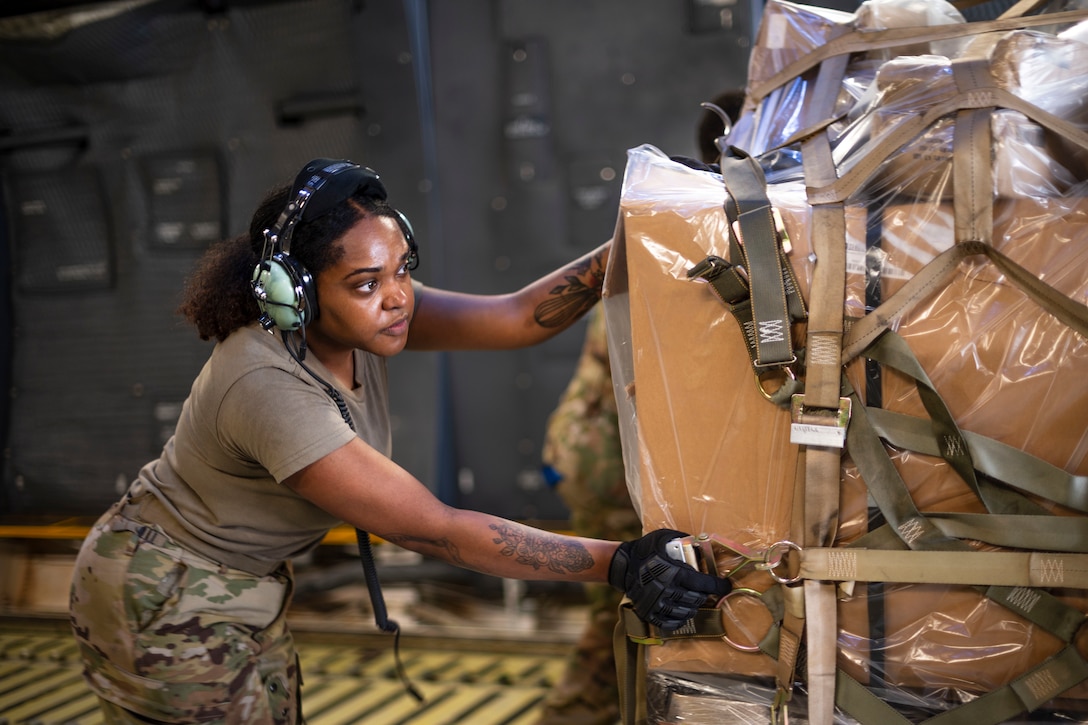 An airman pushes a pallet loaded with cargo.