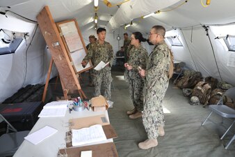 220830-N-UQ872-1001 PORT HUENEME, Calif. (August 30, 2022) Center for Seabees and Facilities Engineering executive officer, Cmdr. Amy Honek, receives a command post briefing from Ensign Sean Kee, Civil Engineer Corps Officers School (CECOS) Basic Class 273 during a five-day field training exercise (FTX). The CECOS FTX is part of a fifteen-week course designed to prepare junior officers for the basics of field operations, leadership and teamwork within Seabee battalions. (U.S. Navy Photo by Daniel Davenport)