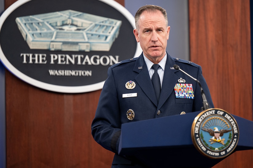 An airman stands behind a lectern with a microphone.