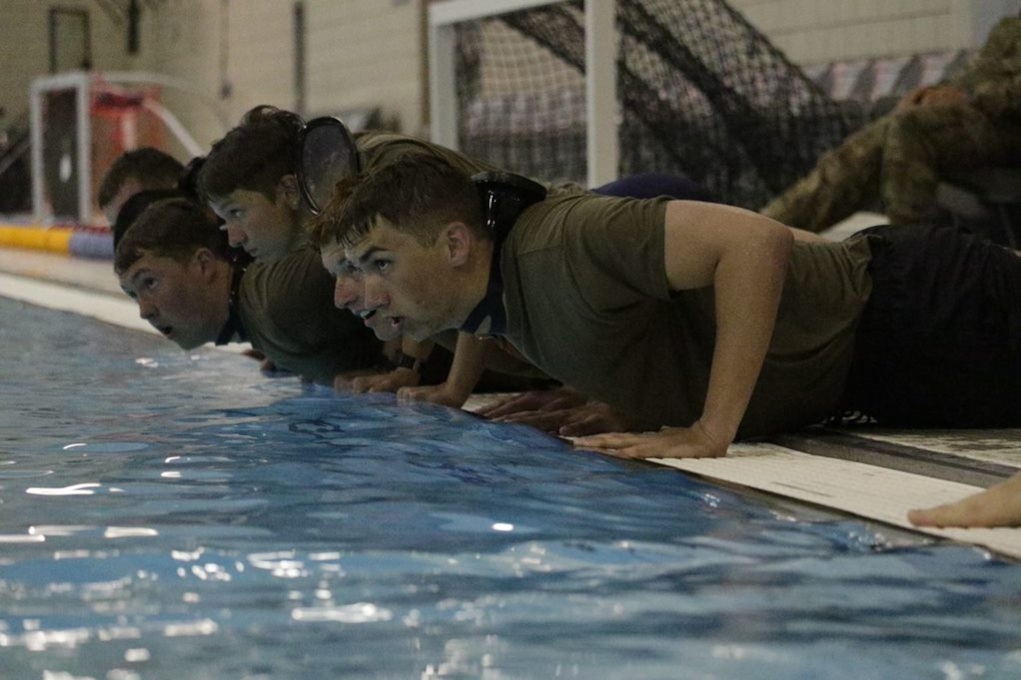 Cadets wait in the prone position by the edge of the pool before beginning 10-ups during the Special Warfare Orientation Course at the U.S. Air Force Academy, Colo., June 8, 2022. The exercise starts in the push-up position followed by an underwater swim across the pool. Most cadets do not have enough confidence in the water before being tested. This exercise and others provided the necessary proper training to build that confidence safely.  (U.S. Air Force Academy courtesy photo)