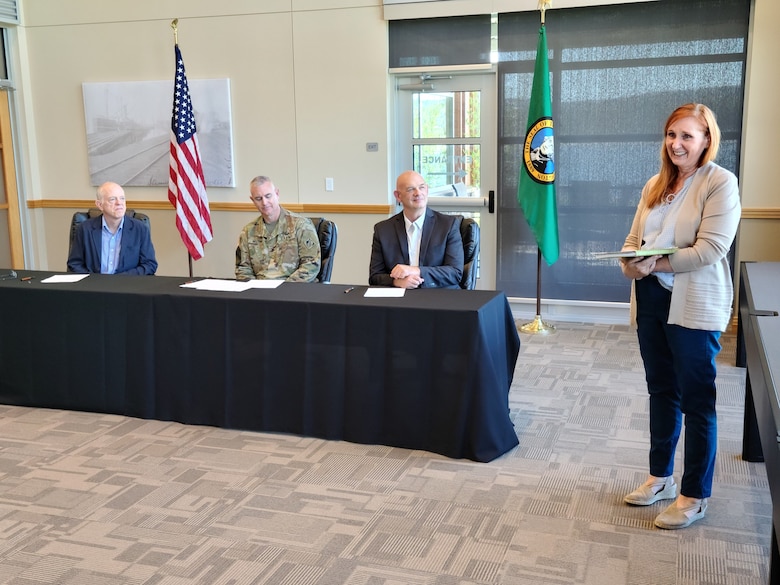 Valerie Ringold, Portland District chief of planning and economics (far-right), explains what a feasibility study is before Army Col. Michael Helton, Portland District commander (center-left), Dan Stahl, Port of Longview chief executive officer (far-left), and Mark Wilson, Port of Kalama executive director (right-center), sign an agreement for a $2.1 million study, Sept. 6 at the Port of Kalama, Washington. Currently, there are very few places on the lower Columbia River to turn large, fully loaded ships. These vessels need to be turned around before passing through Longview, Washington when Pacific Northwest storms force Columbia River Bar closures for unsafe conditions.
