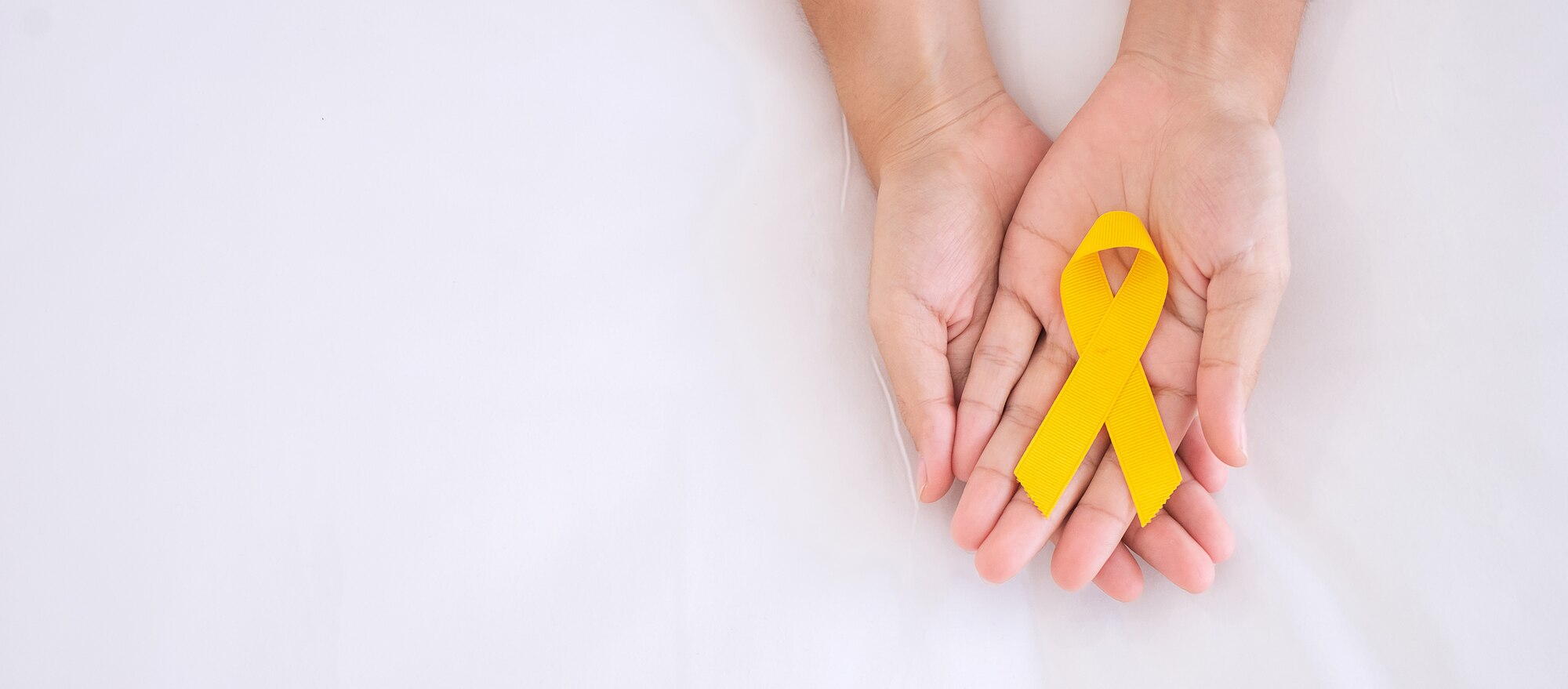 Hands holding a yellow ribbon to signify suicide prevention.