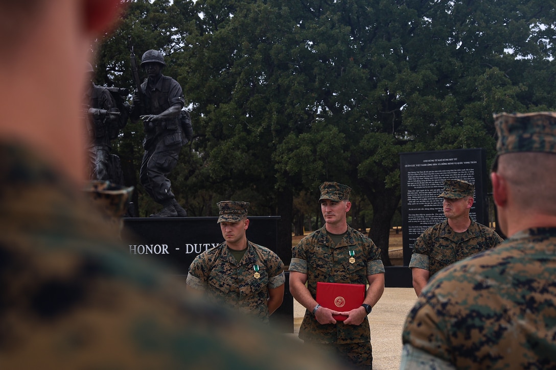 U.S. Marine Corps Staff Sgt. Dalmon Moseley, left, Staff Sgt. Dylan Greene, and Gunnery Sgt. Jamie Self, with Recruiting Substation Arlington, listens to closing remarks during their ceremony in Fort Worth, Texas, Aug. 18, 2022. Moseley, Greene, and Self each earned a Navy and Marine Corps Commendation Medal for saving the life of a man wounded in a shooting in Arlington, Texas, Feb. 5, 2022. (U.S. Marine Corps photo by Lance Cpl. Hannah Hollerud)