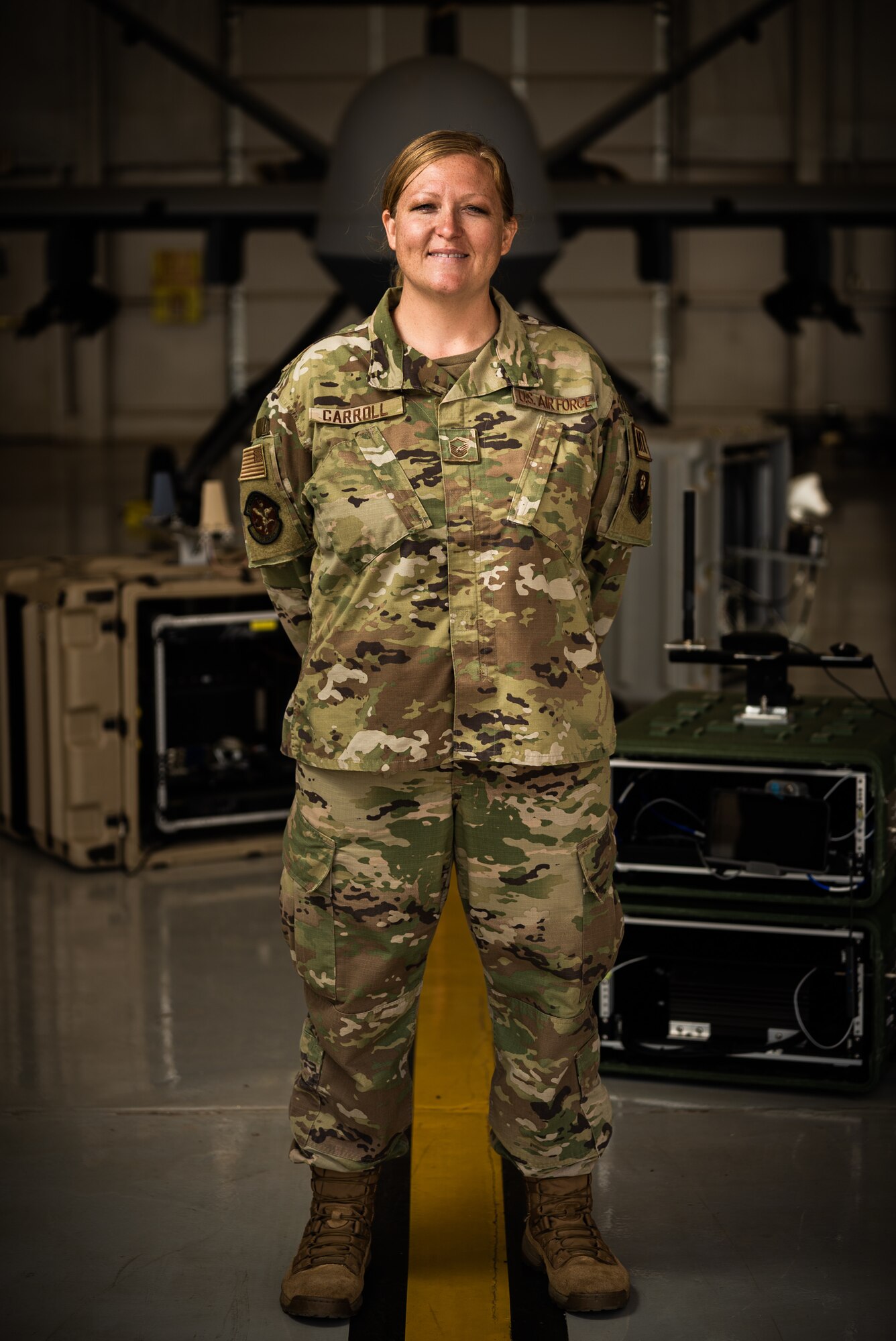 An Air Force Master Sergeant poses for a photo in front of a remotely piloted aircraft.