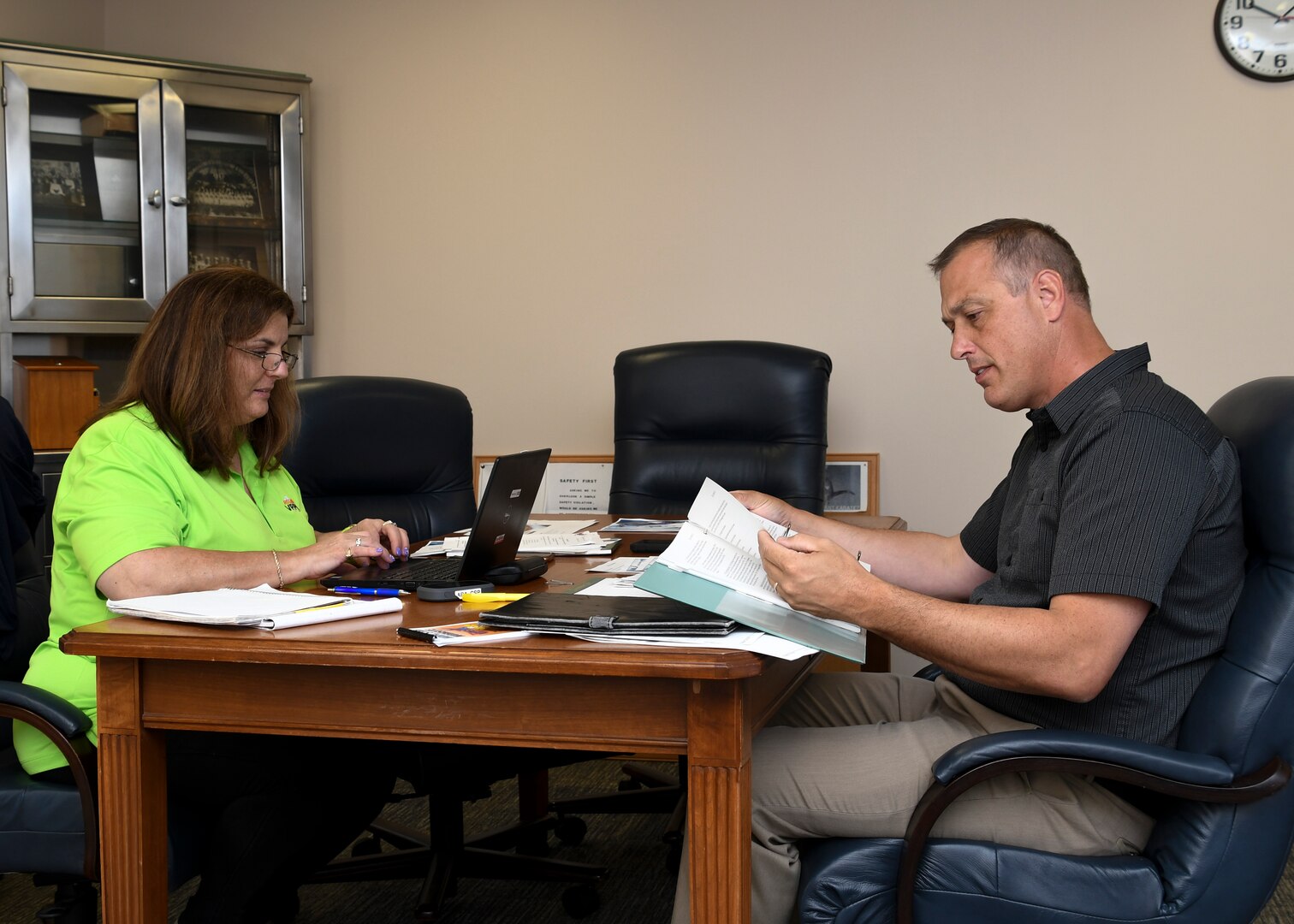 Man sitting at a desk with a woman while reviewing documents.