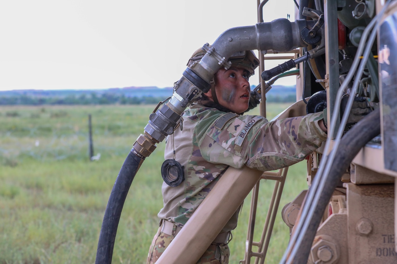 A  soldier looks at fueling equipment.