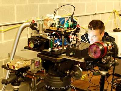 IMAGE: Naval Surface Warfare Center Dahlgren Division Scientist Ryan Stanitski monitors system equipment during a laser data collection event for the Integrated Clip-on Advanced Targeting Sight Dual Band Imager team, who support the Electromagnetic and Sensor Systems Department at Dahlgren. Stanitski and his team collaborated with Integrated Engagement Systems Department personnel to bring about the test event in late May.