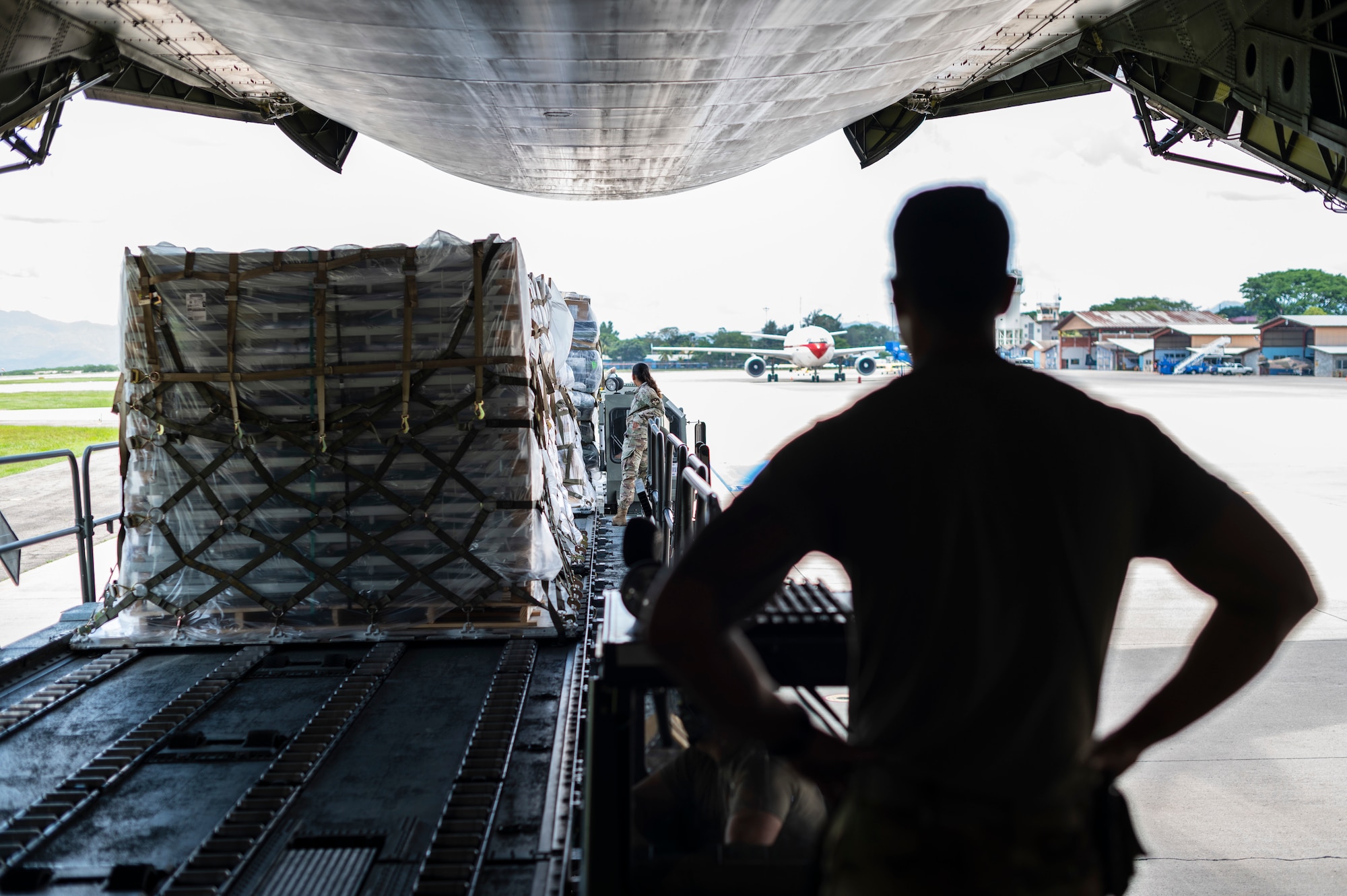 An Airman watches cargo being onloaded from the inside of a large aircraft.