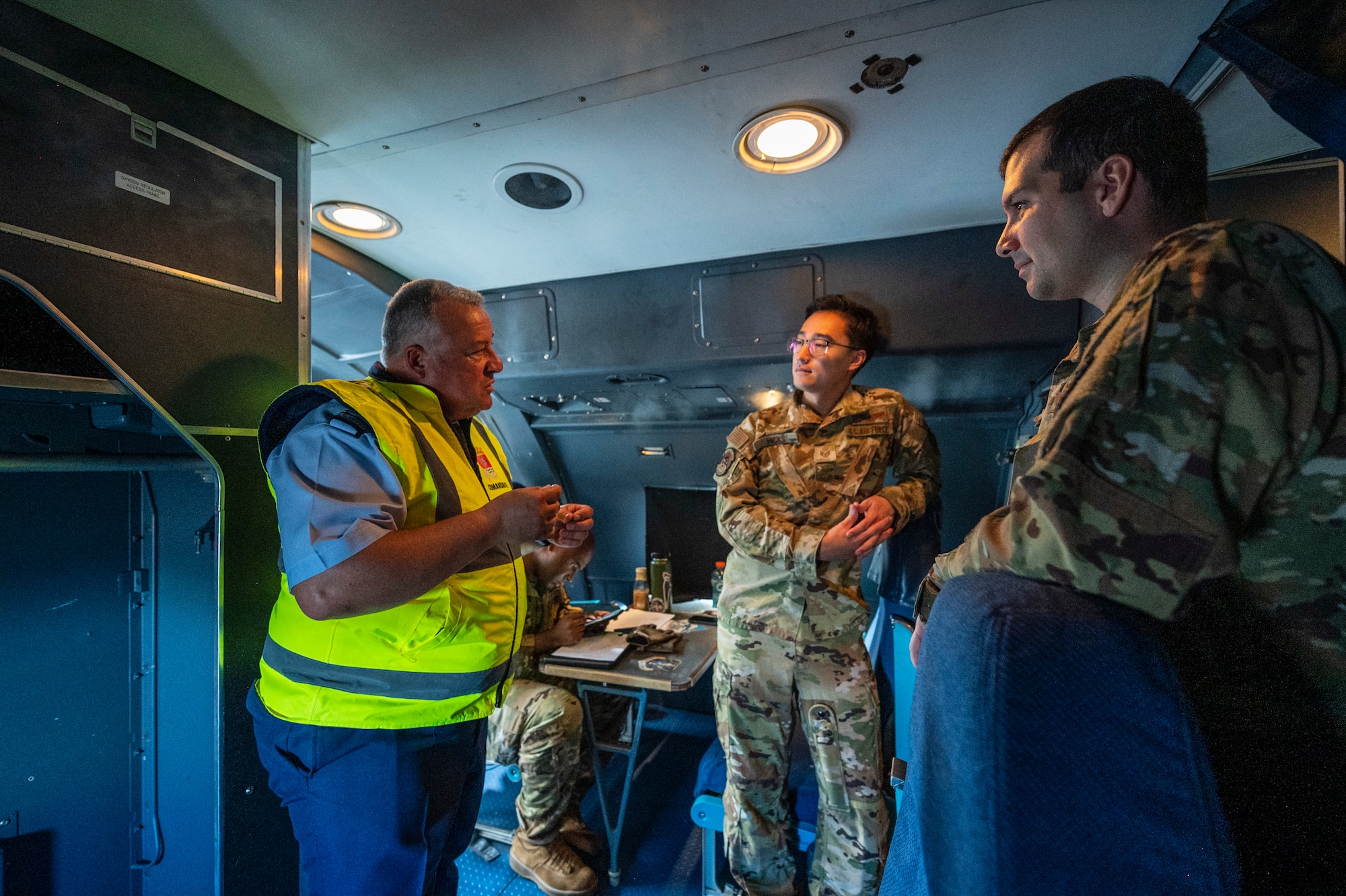 3 Airmen have a conversation in an aircraft.