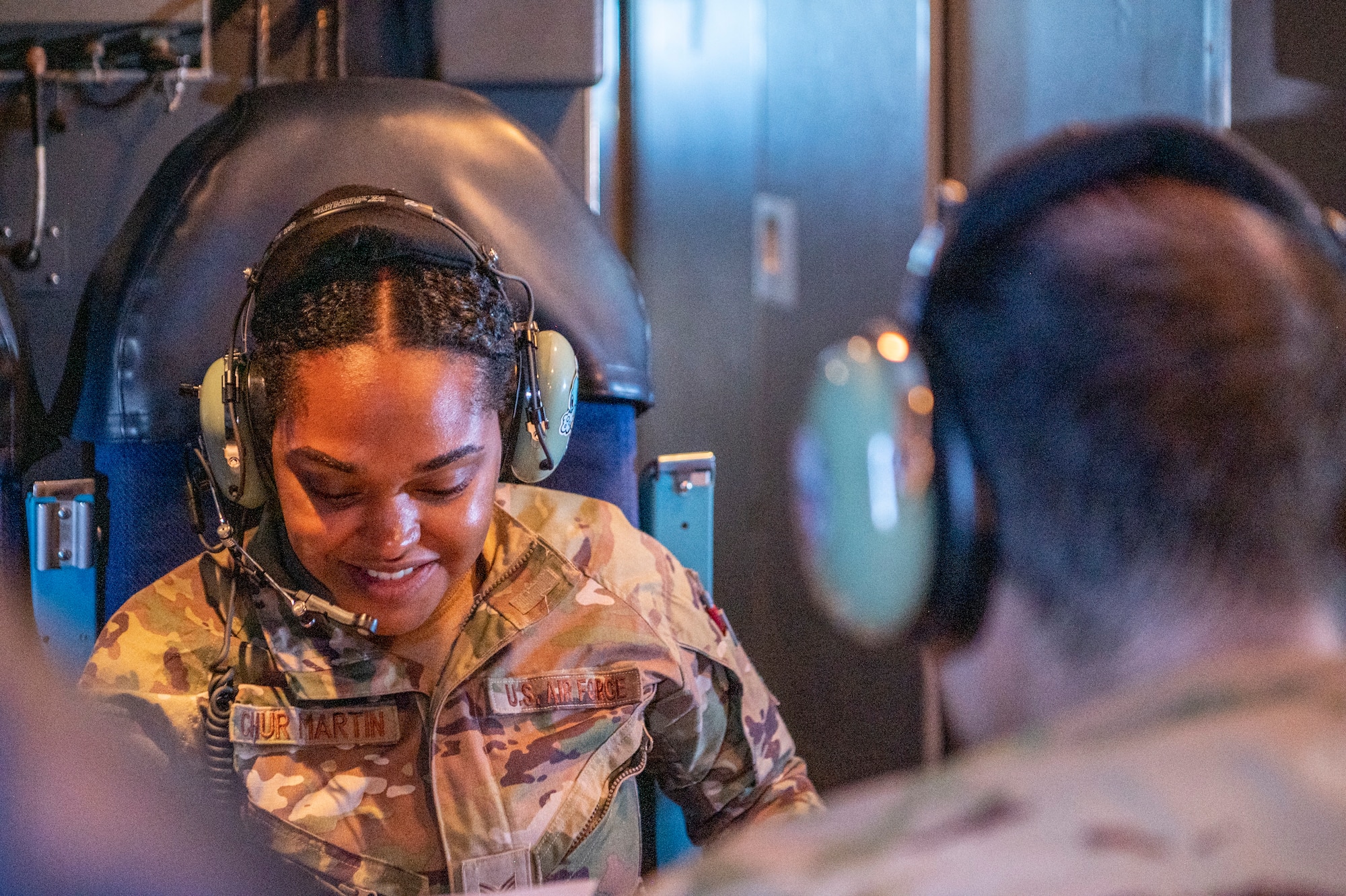 An Airman wears a headset and smiles.