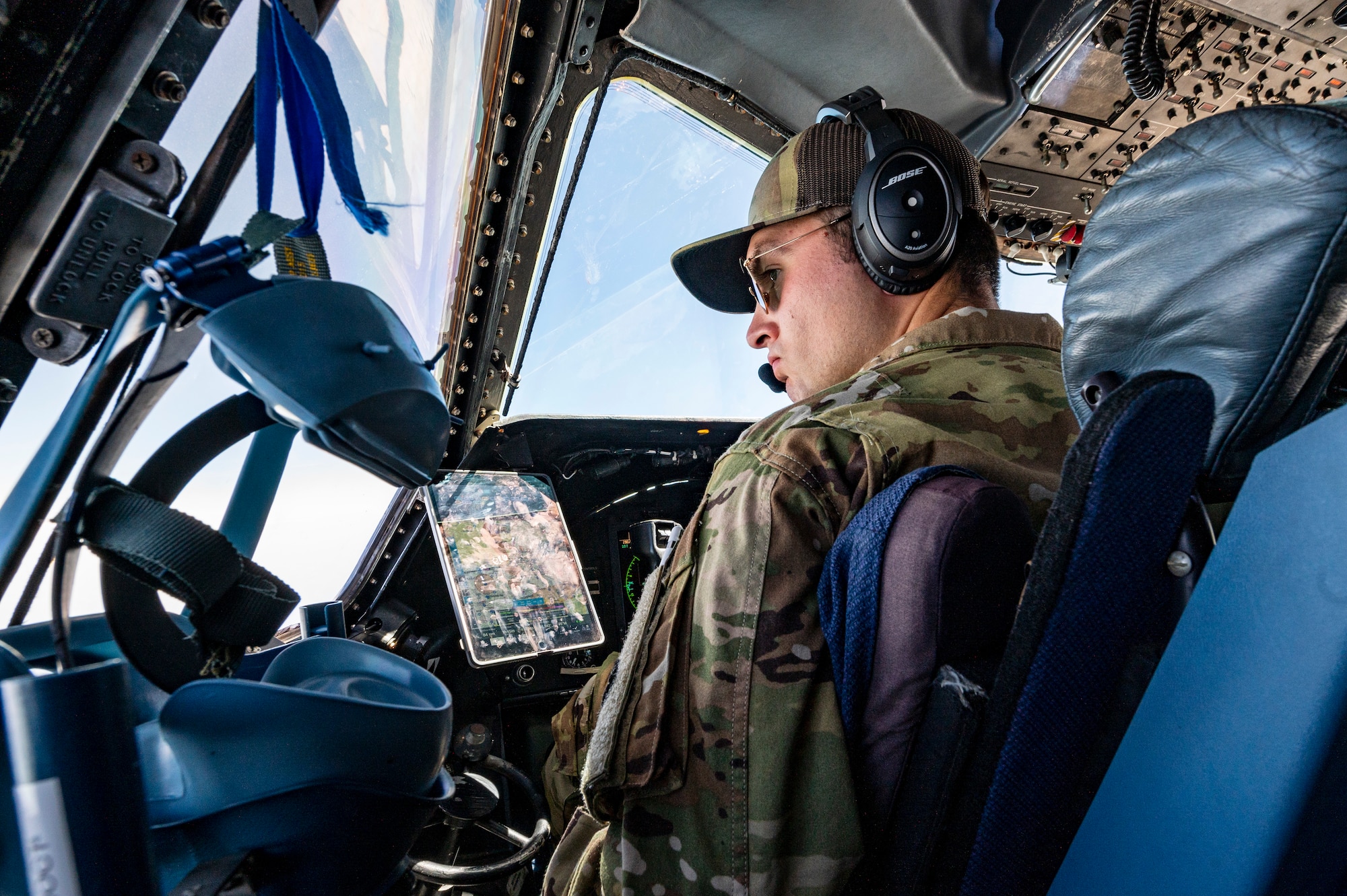 An Airman sits in a pilots seat in an aircraft.