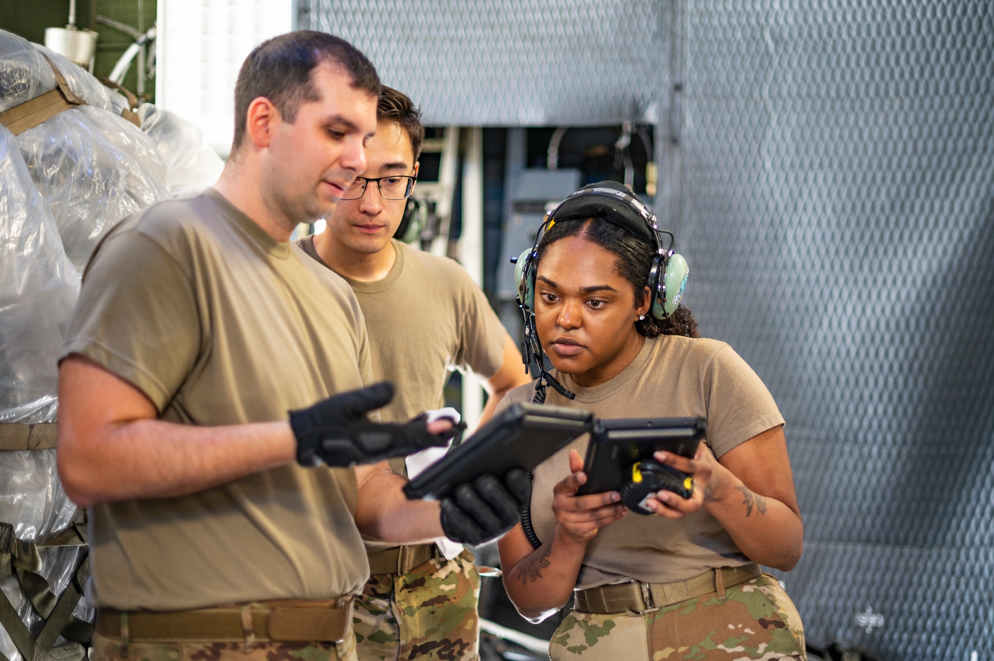 An Airman holds an Ipad and 2 other Airmen read it.